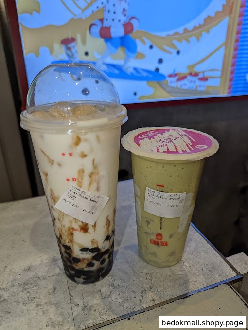 Two bubble tea drinks on a counter with a screen in the background.