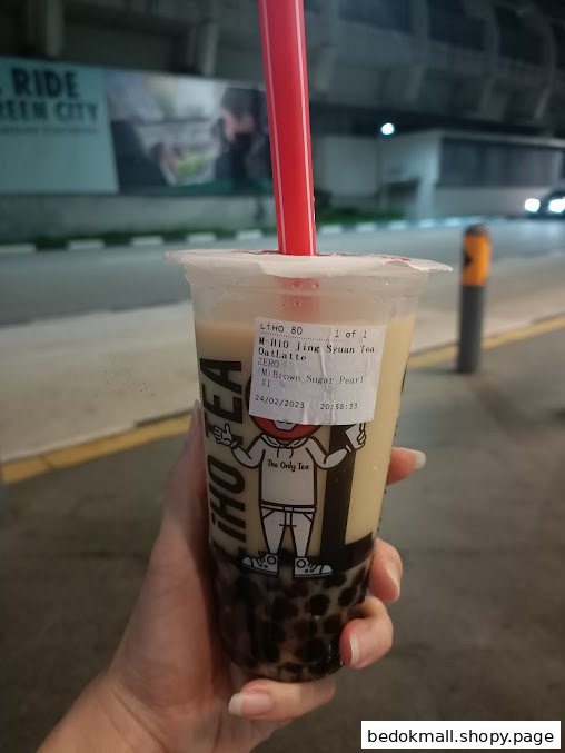 Hand holding a bubble tea cup with a red straw.