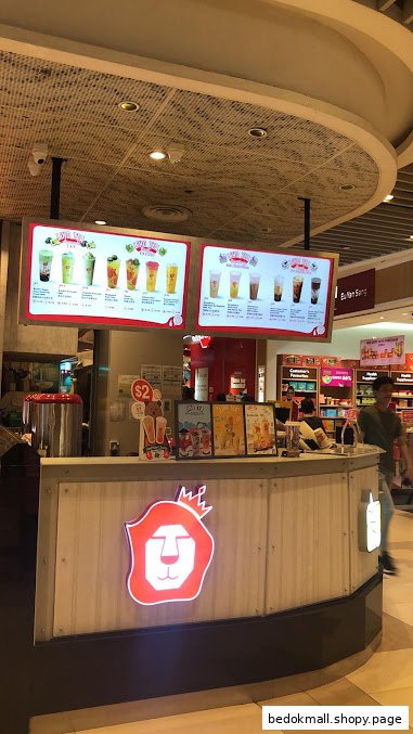 A bubble tea shop counter with digital menus displaying drinks and a lion logo.