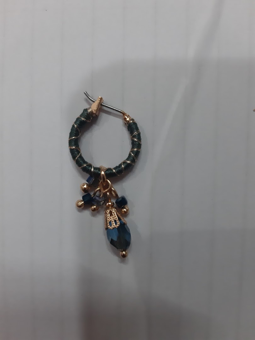 Close-up of a single dark green hoop earring with blue beads and crystal.