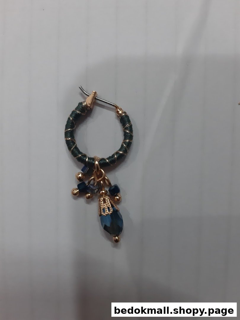 Close-up of a single dark green hoop earring with blue beads and crystal.