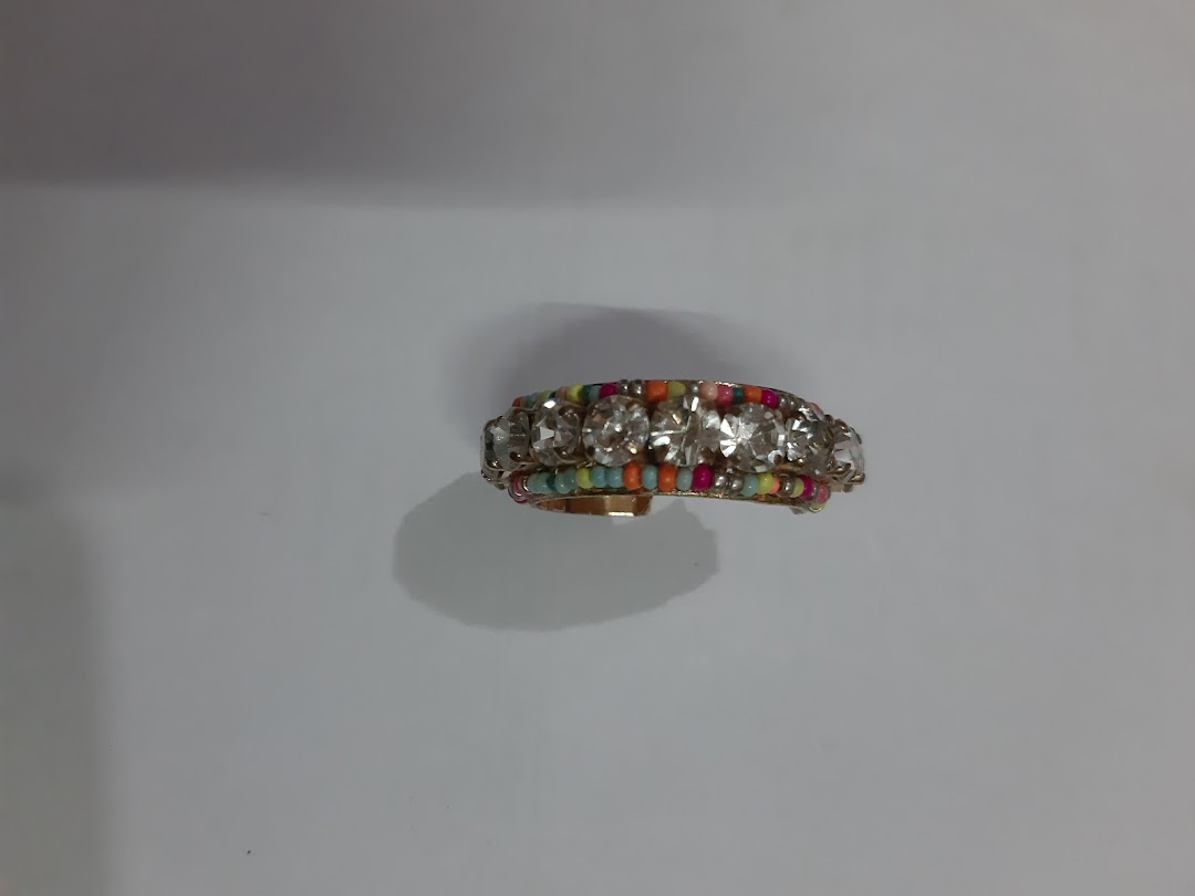 Close-up of a gold-colored ring with clear stones and colorful beads.