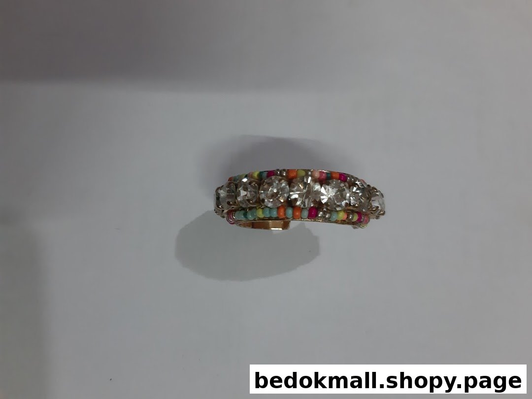 Close-up of a gold-colored ring with clear stones and colorful beads.