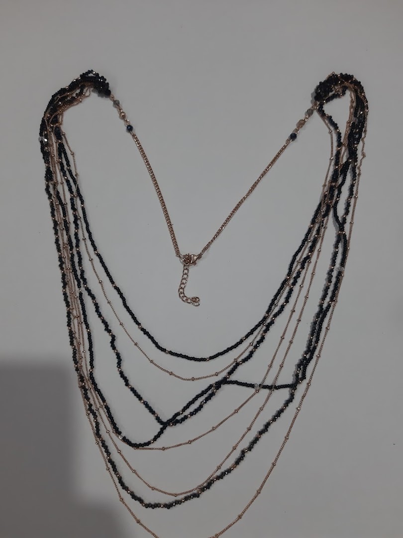 Multi-layered necklace with black beads and gold-colored chains on a white background.