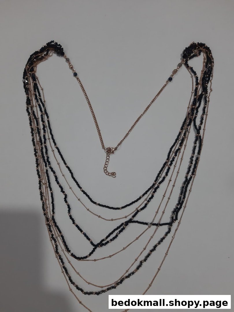 Multi-layered necklace with black beads and gold-colored chains on a white background.