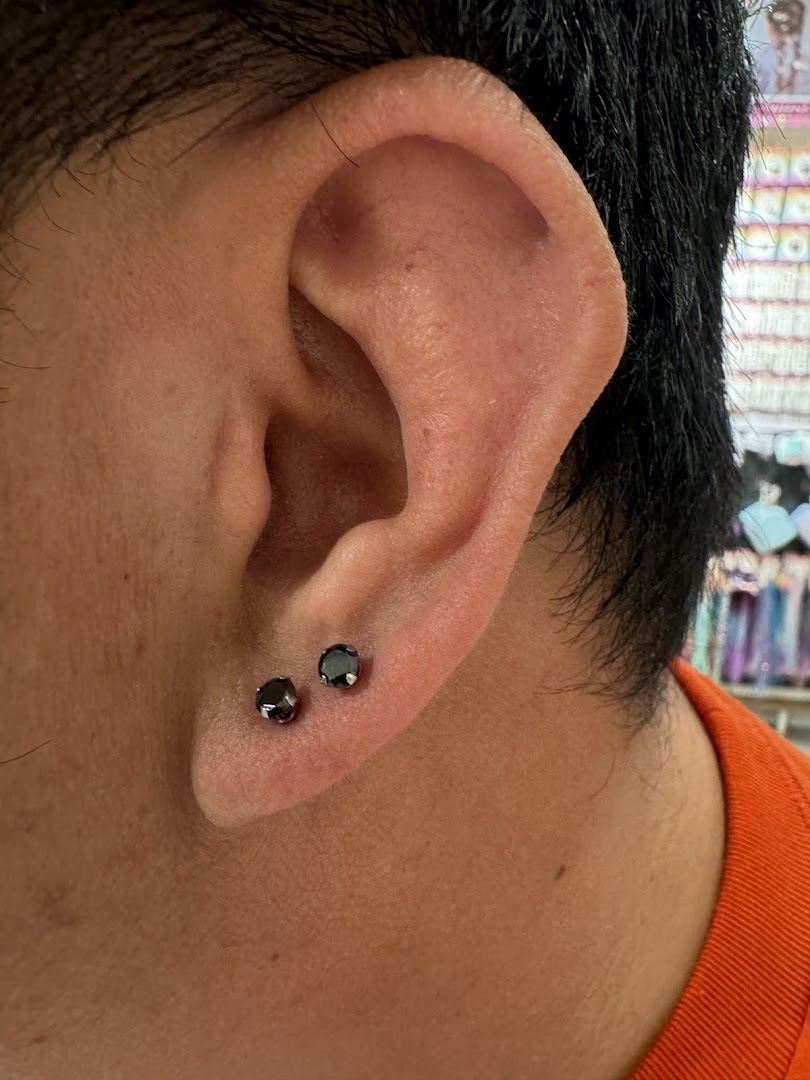 Close-up of an ear with two black stud earrings.