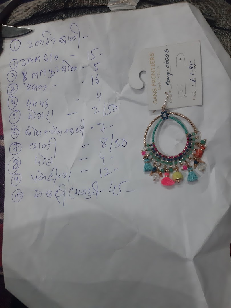 Handwritten list on paper next to a colorful earring with a price tag.