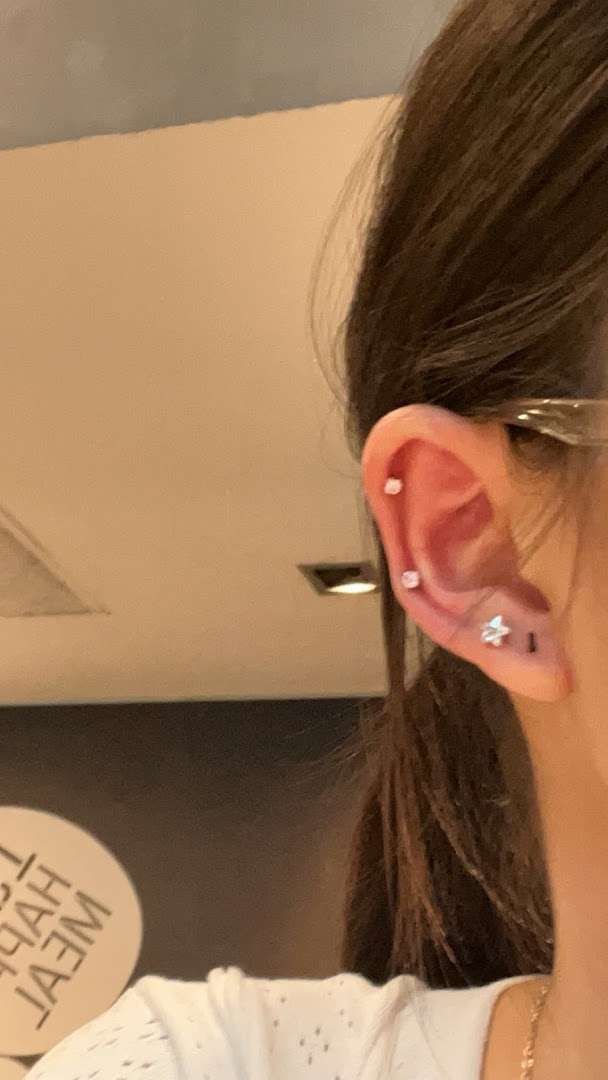 Close-up of a person's ear with multiple piercings, including a star-shaped one.