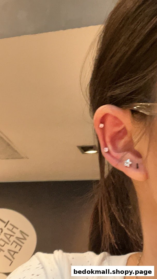 Close-up of a person's ear with multiple piercings, including a star-shaped one.