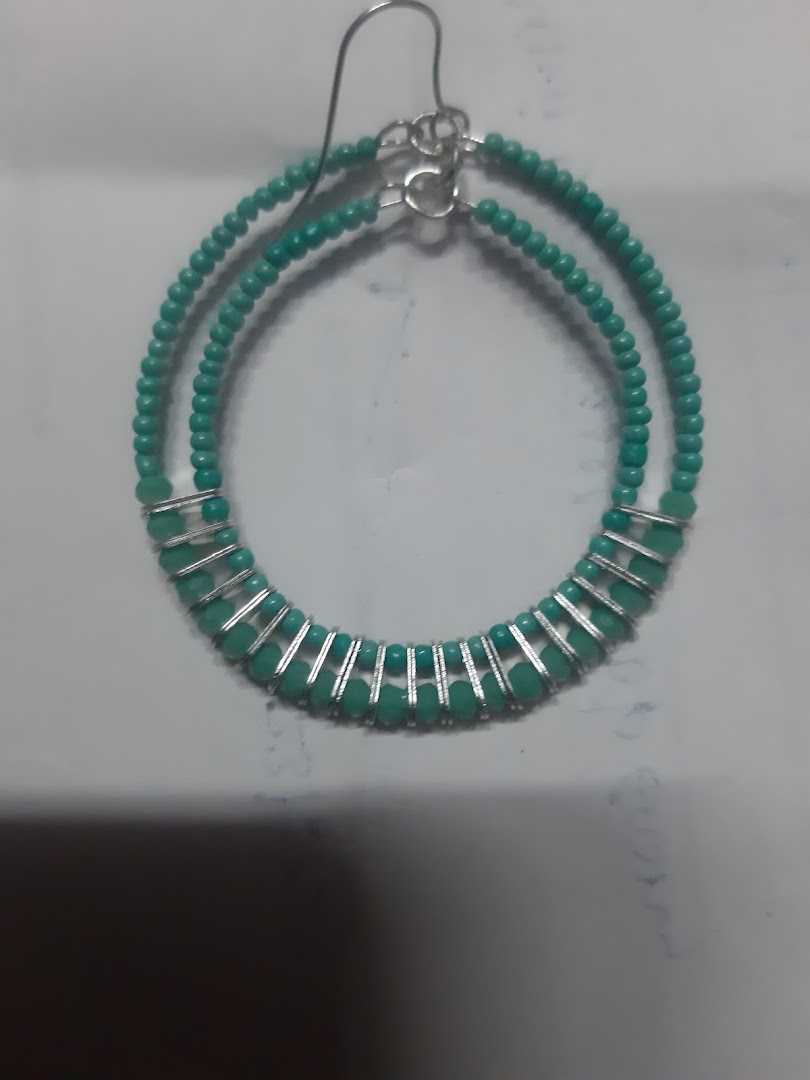 A turquoise beaded hoop earring with silver accents on a white surface.