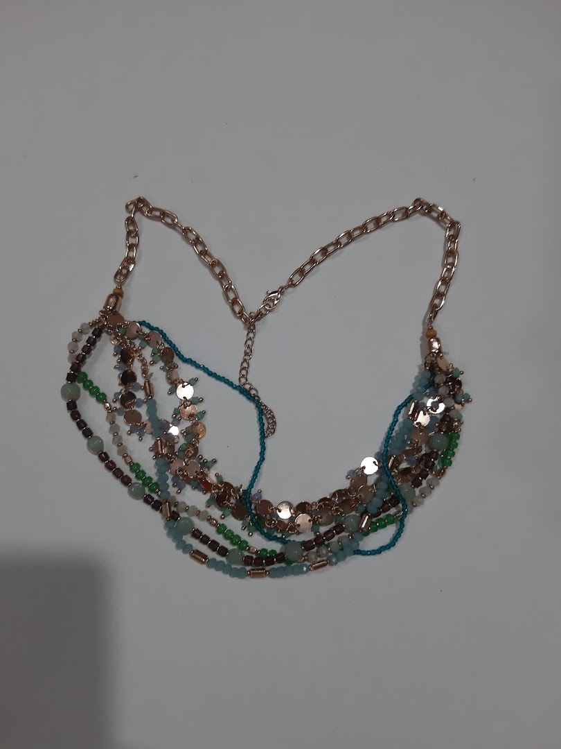 A multi-strand necklace with beads and metallic discs on a light background.