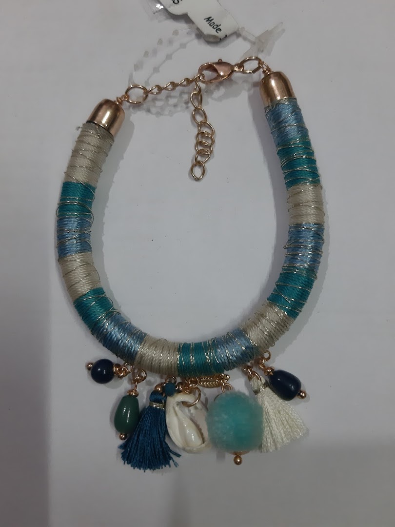 Close-up of a multi-colored bracelet with tassels, beads, and a shell charm.