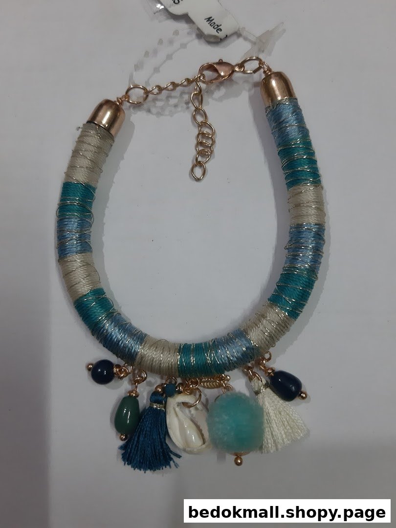 Close-up of a multi-colored bracelet with tassels, beads, and a shell charm.