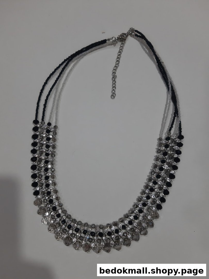 A black and clear beaded necklace on a white background.