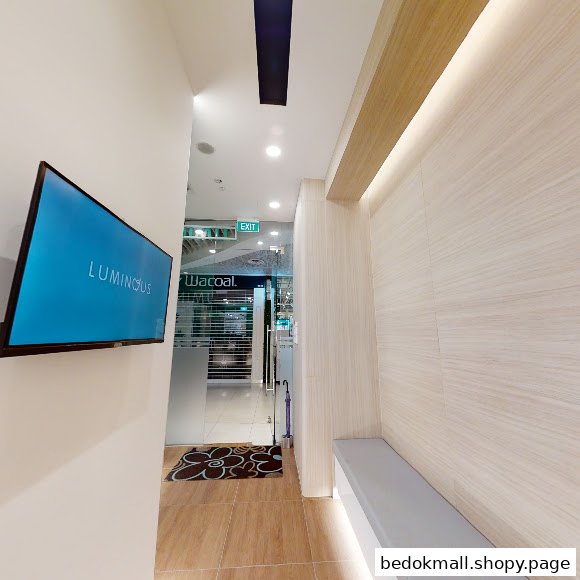 Interior waiting area with TV screen and bench near glass entrance.
