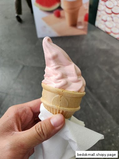 A hand holds a pink soft-serve ice cream cone.