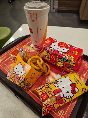 McDonald's food on a tray with Hello Kitty themed packaging and a drink.