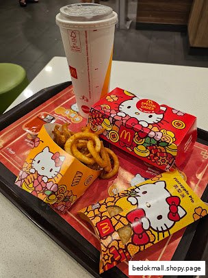 McDonald's food on a tray with Hello Kitty themed packaging and a drink.