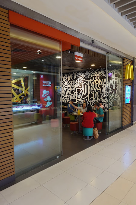 Entrance of a McDonald's restaurant with customers visible inside.