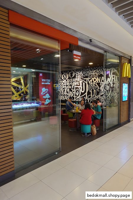 Entrance of a McDonald's restaurant with customers visible inside.