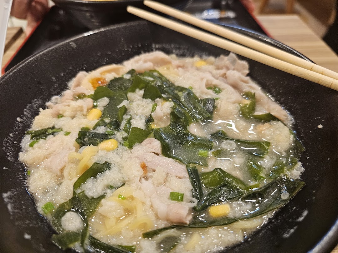 Close-up of a bowl of ramen with pork, seaweed, and chopsticks.