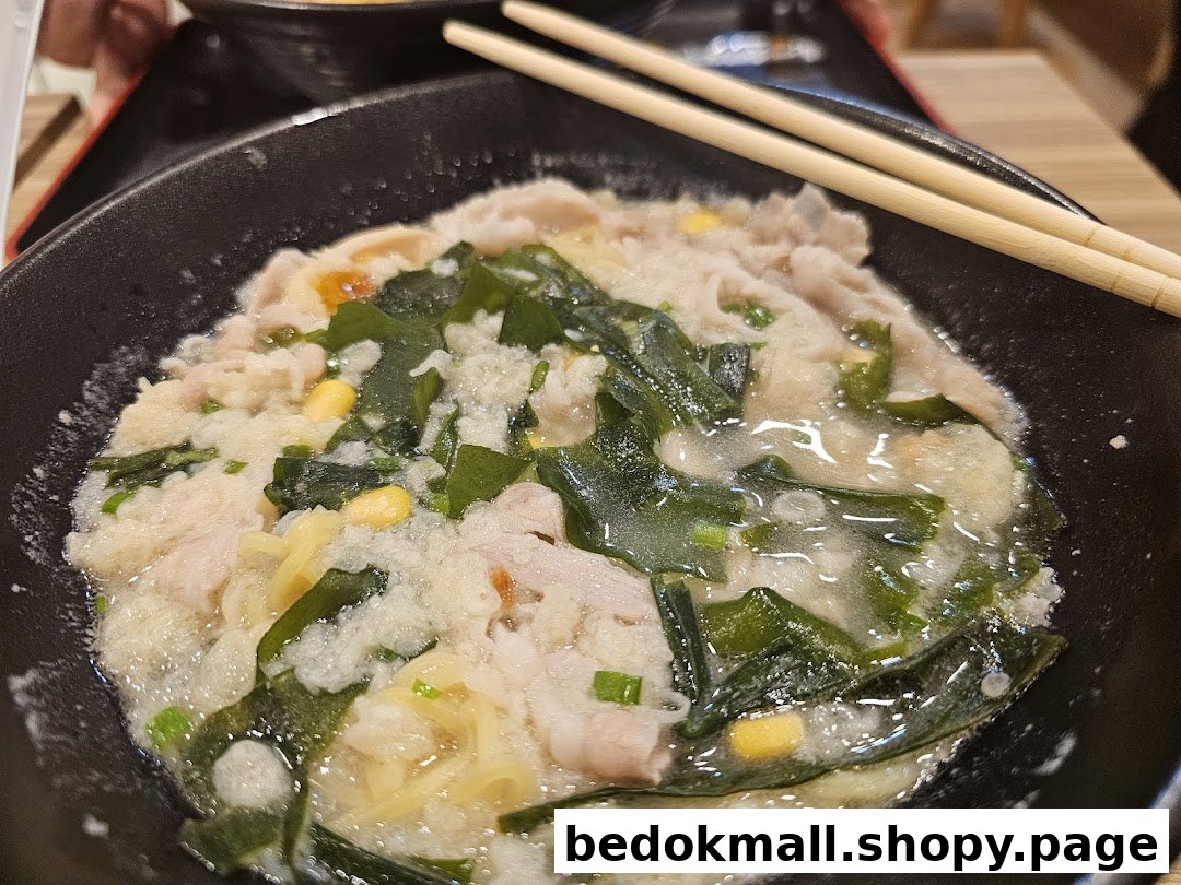 Close-up of a bowl of ramen with pork, seaweed, and chopsticks.