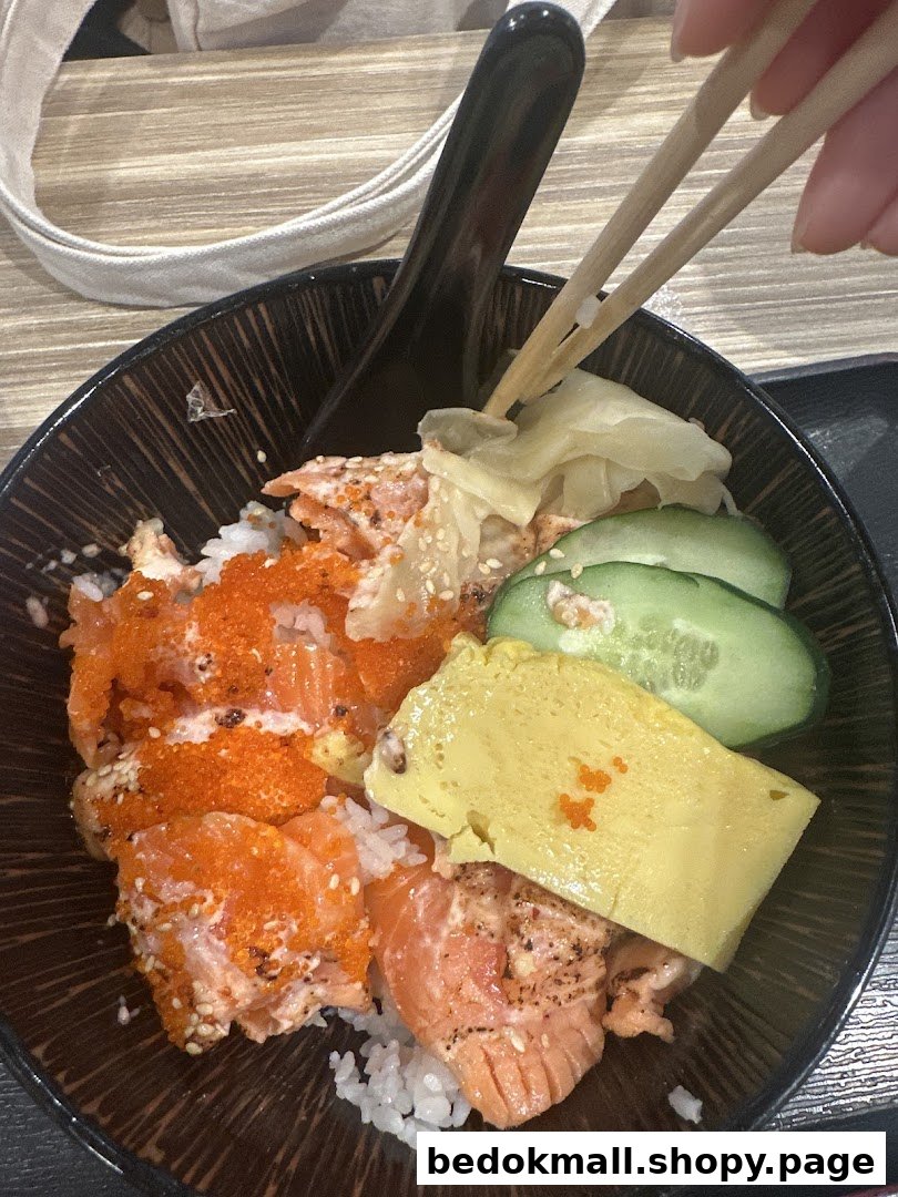 A salmon donburi with egg, cucumber, and roe, being eaten with chopsticks.