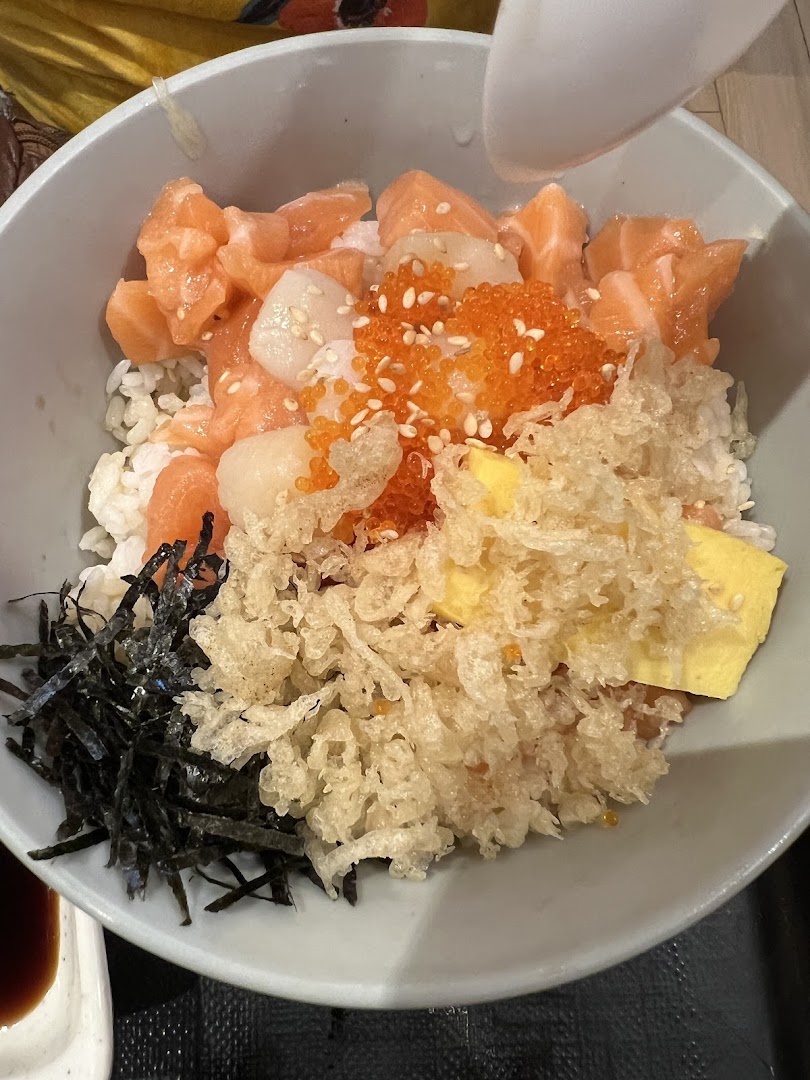 A bowl of rice with salmon, scallops, roe, tempura bits, and seaweed.