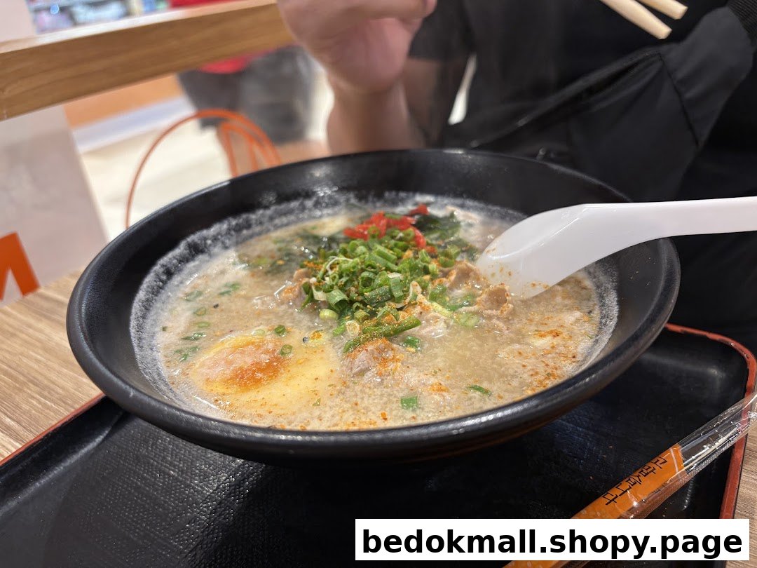 A person eating a bowl of ramen with chopsticks and a spoon.