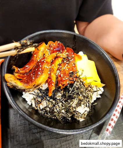 A bowl of unagi donburi with rice, eel, seaweed, and omelet.
