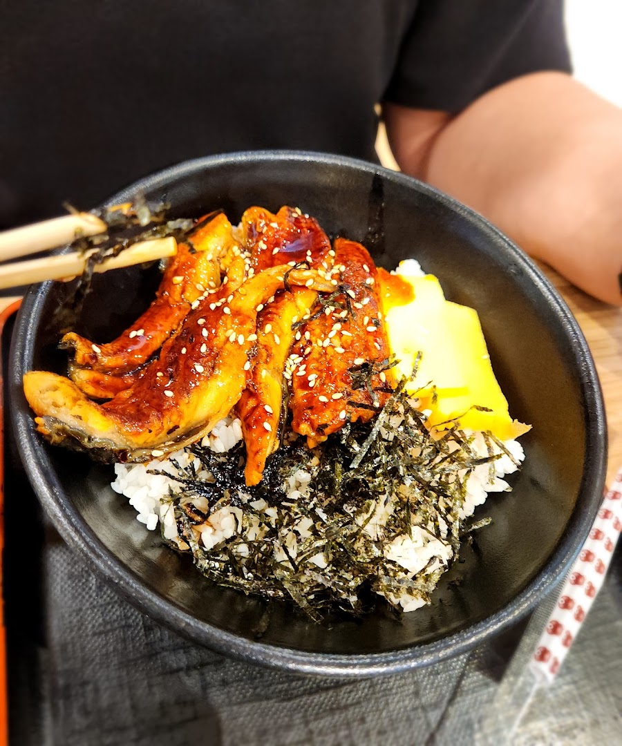 A close-up of a bowl of eel rice with seaweed and egg.
