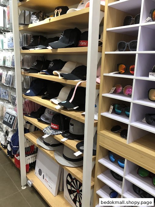 Shelves displaying various hats, caps, and sunglasses inside a retail store.