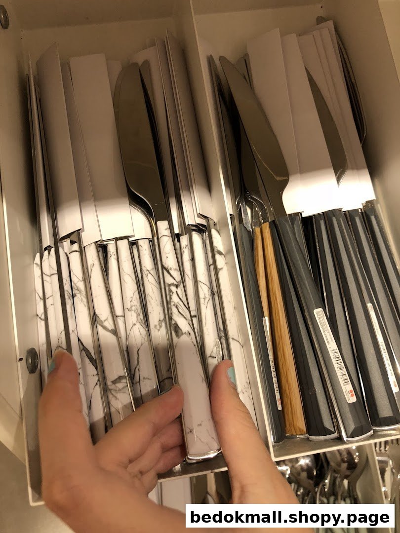 Hand holding a marble-handled knife among other cutlery in a display.