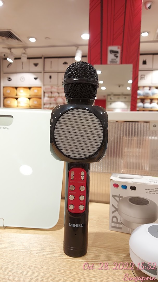 A black MINISO microphone with speaker on display in a retail store.