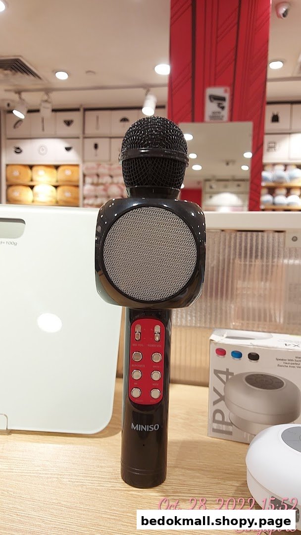 A black MINISO microphone with speaker on display in a retail store.