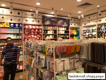 Interior view of a MINISO store displaying various products and a customer.