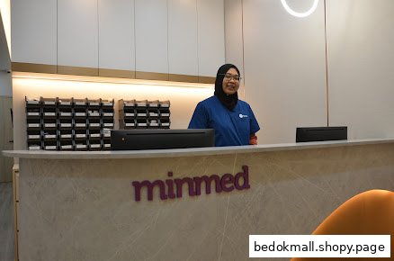 A staff member stands behind the Minmed clinic reception desk.