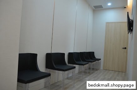 Interior view of a waiting area with black chairs and a wooden door.