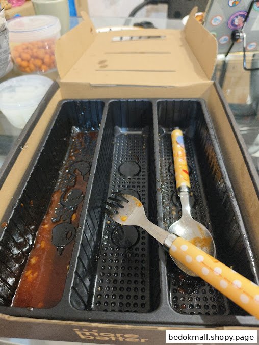 Used food container with leftover sauce and cutlery.