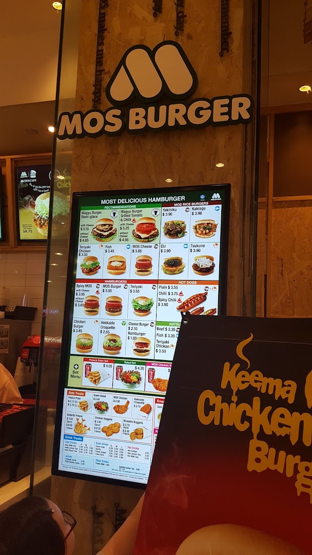 Digital menu board displaying burgers, hot dogs, and other food items at MOS Burger.