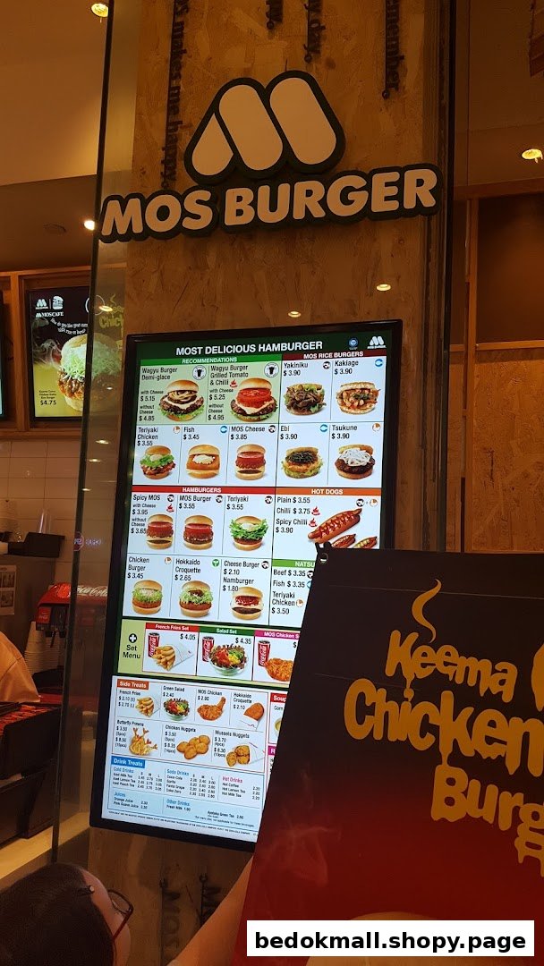 Digital menu board displaying burgers, hot dogs, and other food items at MOS Burger.