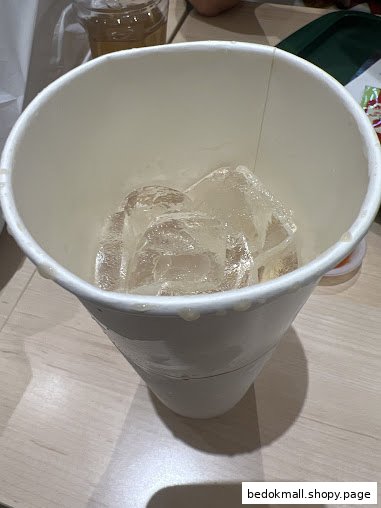 A white paper cup filled with ice cubes on a table.