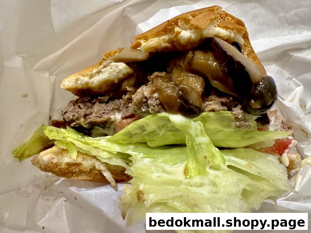 Close-up of a burger with patty, mushrooms, lettuce, and tomato in wrapping.