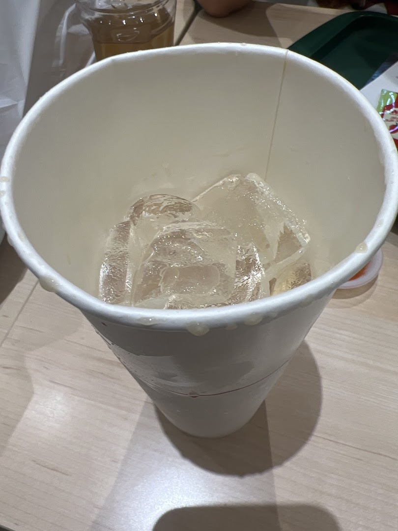 A white paper cup filled with ice cubes on a table.