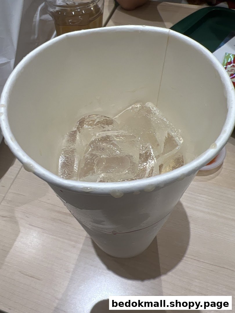 A white paper cup filled with ice cubes on a table.