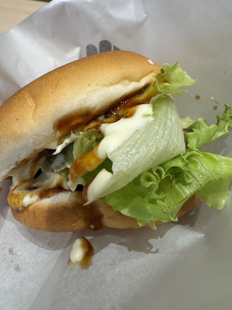 A close-up of a burger with lettuce and sauces on white paper.