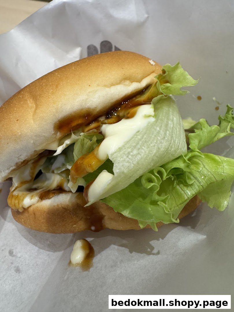 A close-up of a burger with lettuce and sauces on white paper.