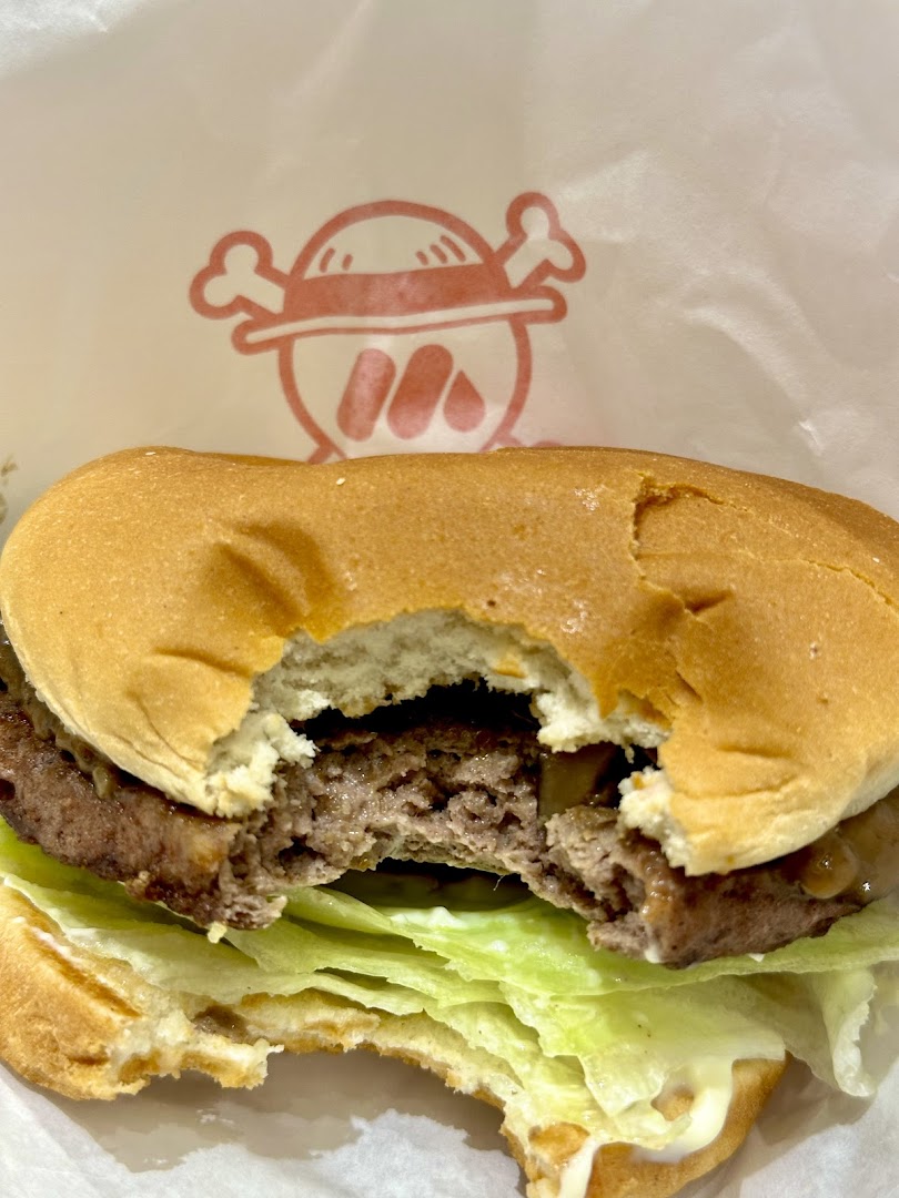A partially eaten burger with lettuce and patty, on a wrapper with a logo.