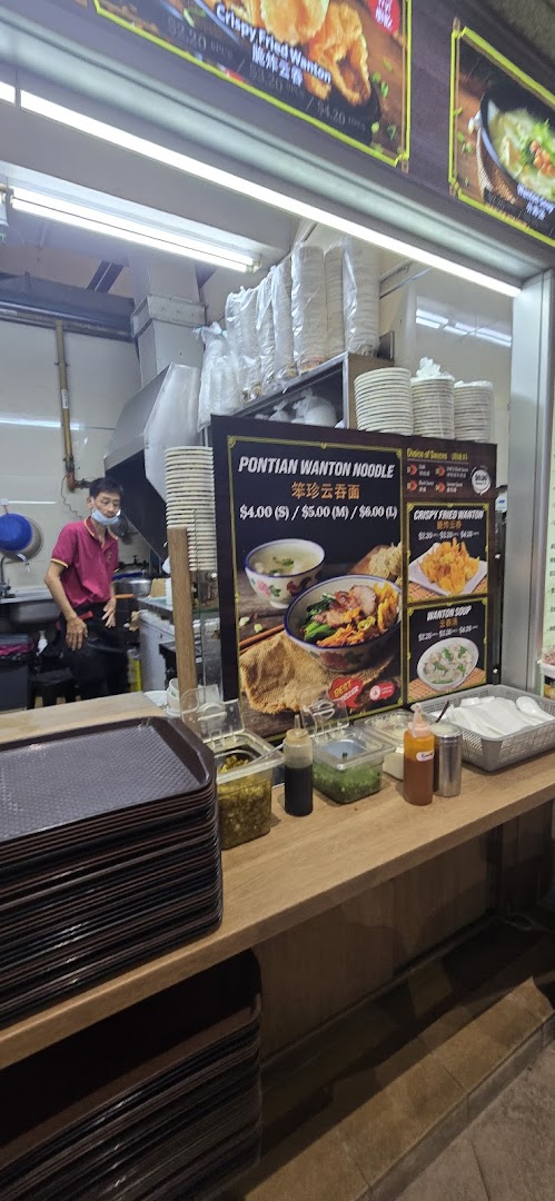 Interior view of a food stall with a menu board, staff, and counter.