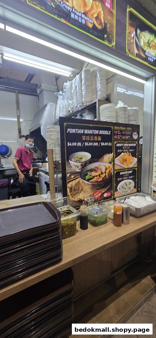 Interior view of a food stall with a menu board, staff, and counter.